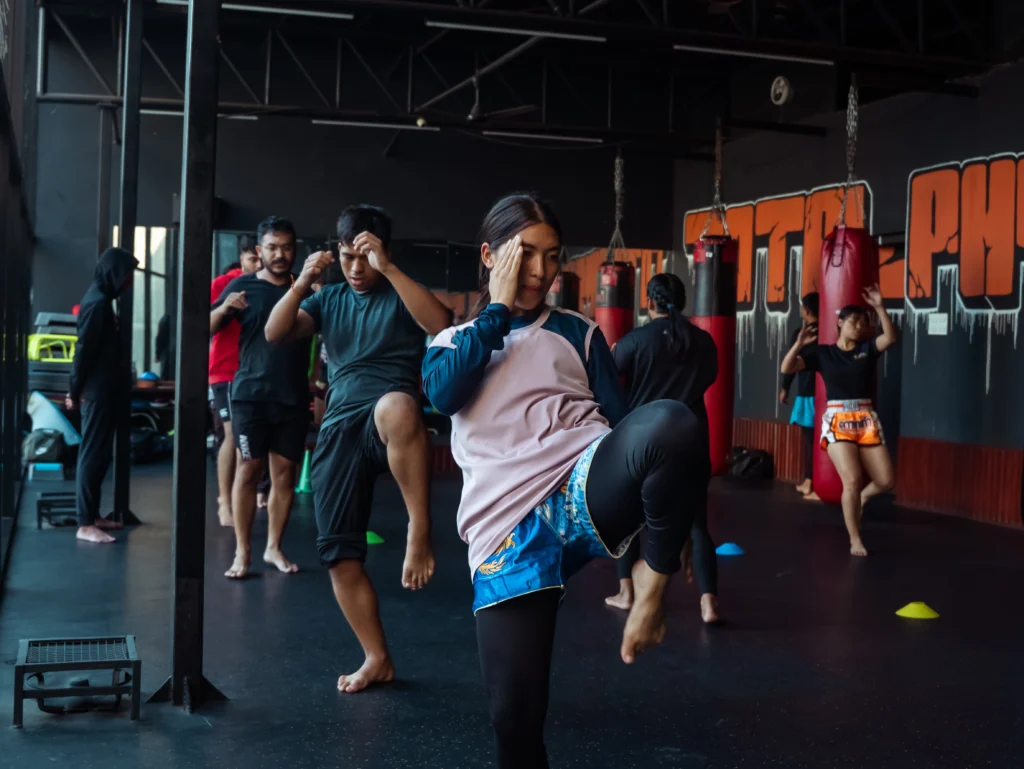 Athletes practicing Muay Thai striking and pad work inside the TPFC (Total Physical Fitness Center) Muay Thai gym.